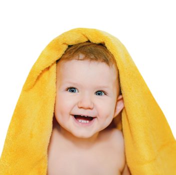 Happy little baby under a yellow towel isolated in white background.